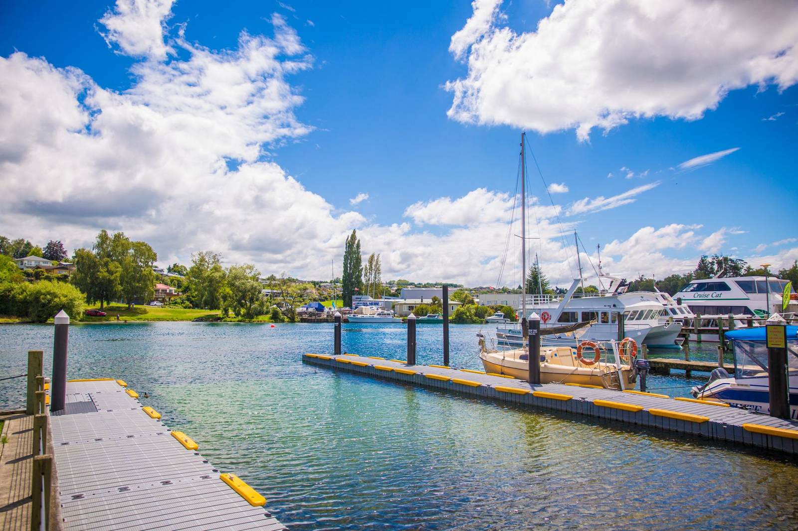 A small cream-colored boat at a sunny dock on clear, light water under a blue sky.